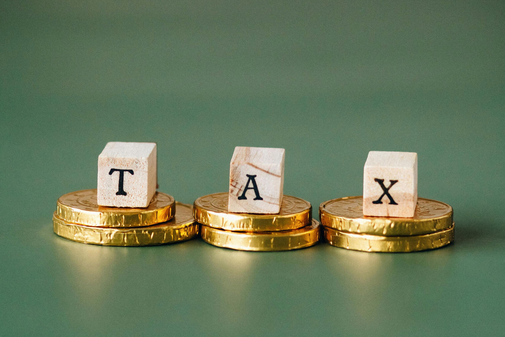 The letters "TAX" held up on coins